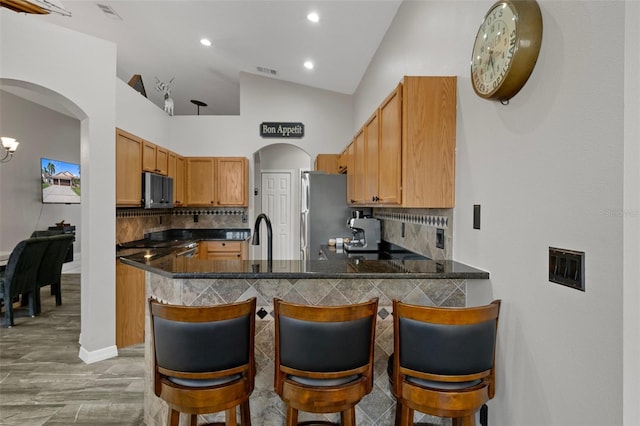 1862 Wood Bend St, Tarpon Springs, FL 34689 - kitchen featuring appliances with stainless steel finishes, arched walkways, vaulted ceiling, backsplash, and dark countertops