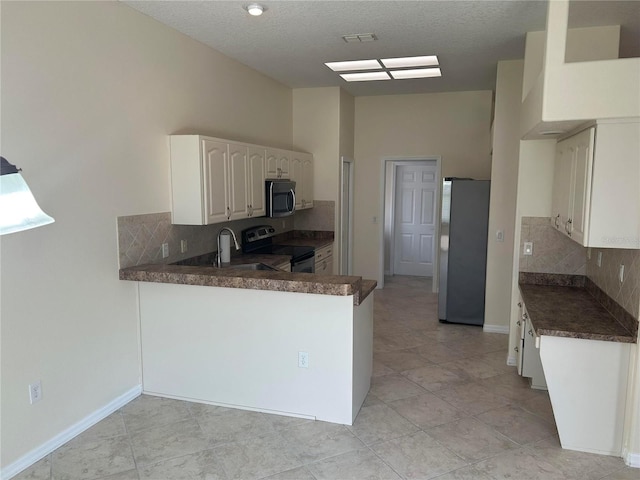 11520 Lounds Ct, New Port Richey, FL 34654 - kitchen with stainless steel appliances, dark countertops, tasteful backsplash, a peninsula, and white cabinetry