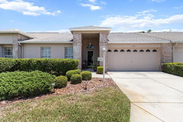 1142 Wolford Dr, Trinity, FL 34655 - view of front of house with a garage, concrete driveway, stucco siding, and roof with shingles
