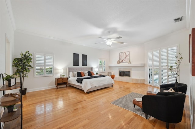 1471 N Jasmine Ave, Tarpon Springs, FL 34689 - bedroom featuring crown molding, light wood finished floors, a glass covered fireplace, baseboards, and ceiling fan