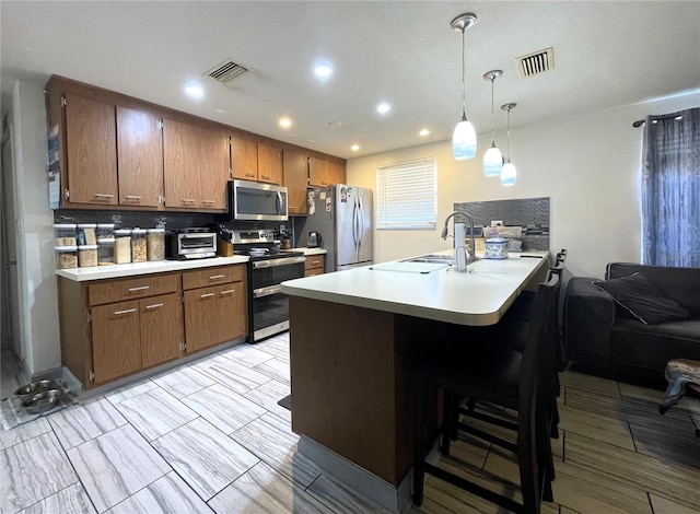 7534 Briarwood Dr, Port Richey, FL 34668 - kitchen featuring appliances with stainless steel finishes, light countertops, a kitchen bar, hanging light fixtures, and recessed lighting