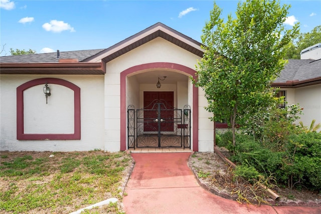 128 Oak Lake Dr, Spring Hill, FL 34608 - entrance to property featuring a shingled roof, stucco siding, and a gate