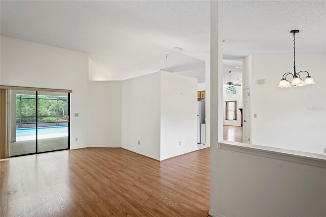 128 Oak Lake Dr, Spring Hill, FL 34608 - empty room featuring wood finished floors, baseboards, a ceiling fan, high vaulted ceiling, and a chandelier