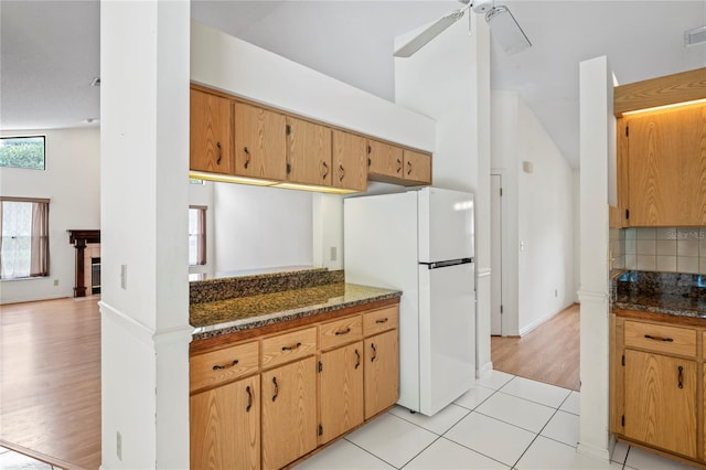 128 Oak Lake Dr, Spring Hill, FL 34608 - kitchen featuring freestanding refrigerator, backsplash, a ceiling fan, dark stone counters, and light wood-style floors