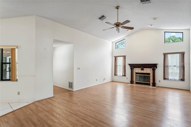 128 Oak Lake Dr, Spring Hill, FL 34608 - unfurnished living room with a ceiling fan, wood finished floors, high vaulted ceiling, a fireplace, and a textured ceiling