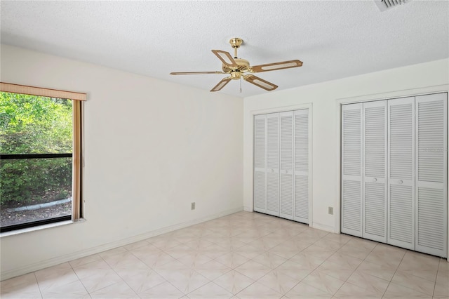 128 Oak Lake Dr, Spring Hill, FL 34608 - unfurnished bedroom with two closets, a textured ceiling, ceiling fan, baseboards, and light flooring