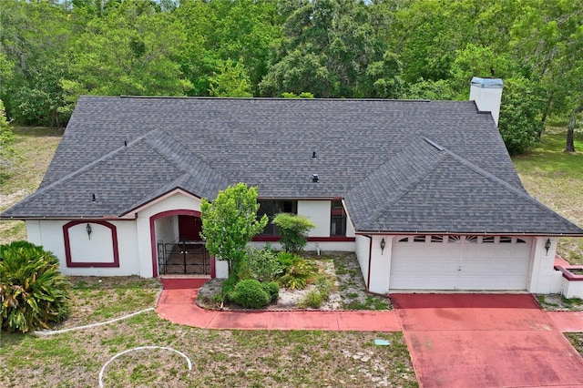 128 Oak Lake Dr, Spring Hill, FL 34608 - view of front of house featuring roof with shingles, a chimney, an attached garage, concrete driveway, and stucco siding