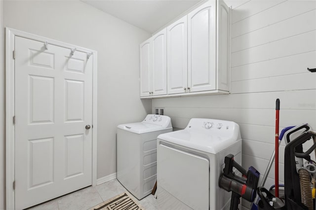 12313 Criollo Rd, Spring Hill, FL 34610 - laundry room featuring cabinet space, washing machine and dryer, light tile patterned floors, and wooden walls