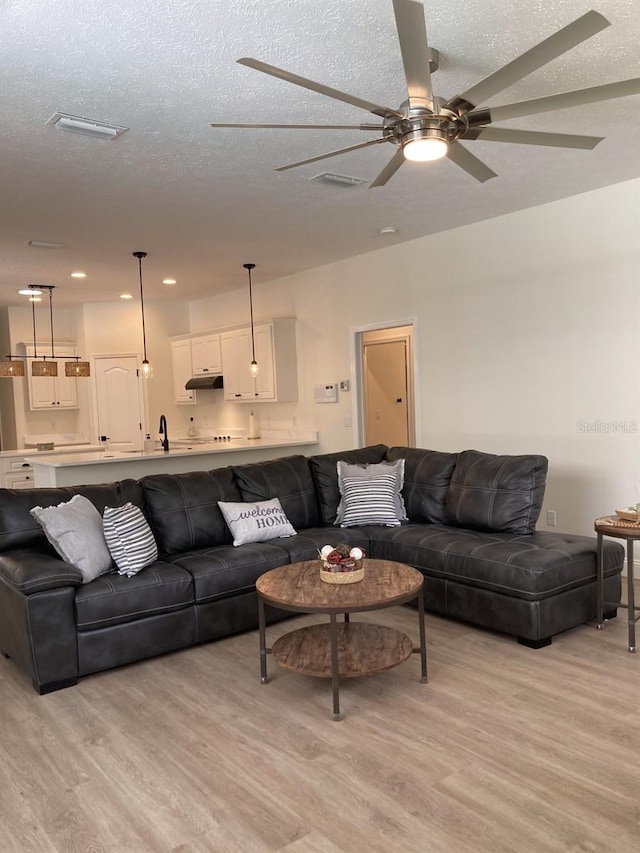 2543 E Marcia St, Inverness, FL 34453 - living room with light wood-style floors, a ceiling fan, a textured ceiling, and recessed lighting