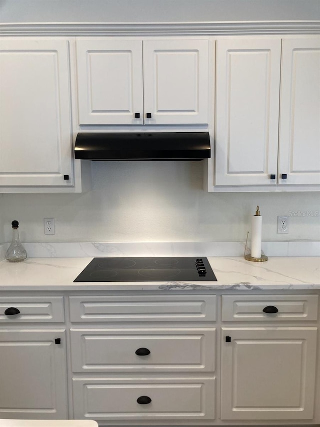 2543 E Marcia St, Inverness, FL 34453 - kitchen featuring under cabinet range hood, black electric cooktop, white cabinetry, and light stone countertops