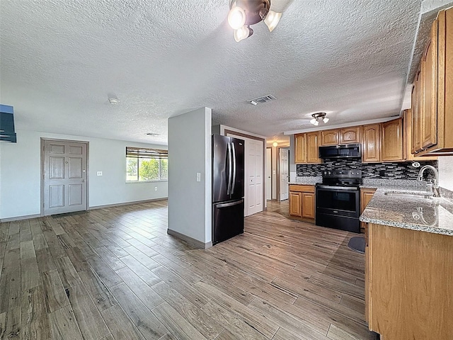 6601 Nautical Isle, Hudson, FL 34667 - kitchen featuring black appliances, a sink, brown cabinetry, baseboards, and wood finished floors