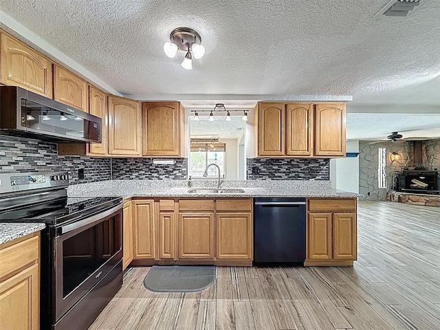 6601 Nautical Isle, Hudson, FL 34667 - kitchen with black appliances, a sink, a textured ceiling, light wood-style flooring, and backsplash