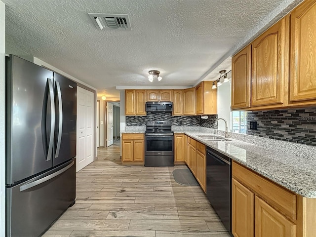6601 Nautical Isle, Hudson, FL 34667 - kitchen featuring black appliances, a sink, a textured ceiling, light wood-style floors, and backsplash