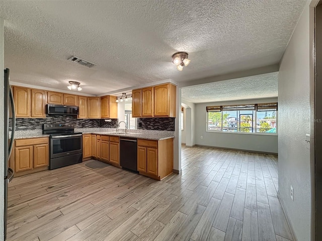 6601 Nautical Isle, Hudson, FL 34667 - kitchen with black appliances, light wood-style floors, a textured ceiling, tasteful backsplash, and baseboards