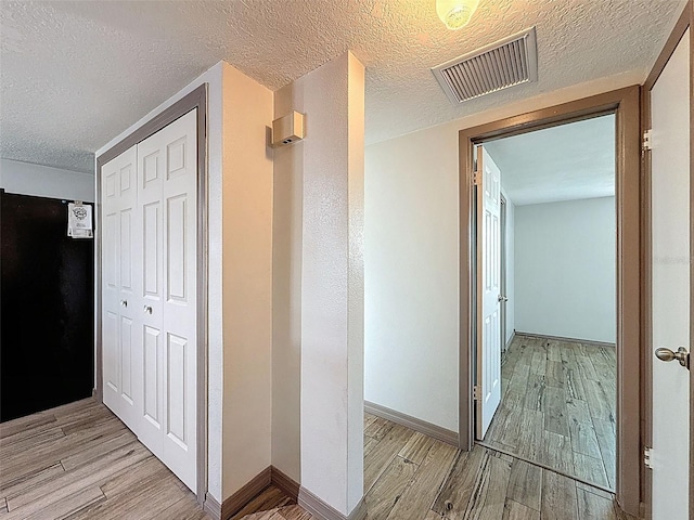 6601 Nautical Isle, Hudson, FL 34667 - corridor with light wood-style flooring, a textured ceiling, and baseboards