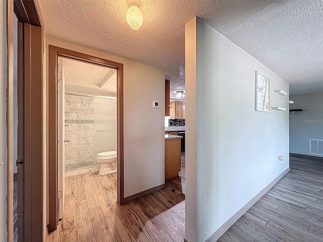 6601 Nautical Isle, Hudson, FL 34667 - hallway featuring light wood-type flooring, a textured ceiling, and baseboards
