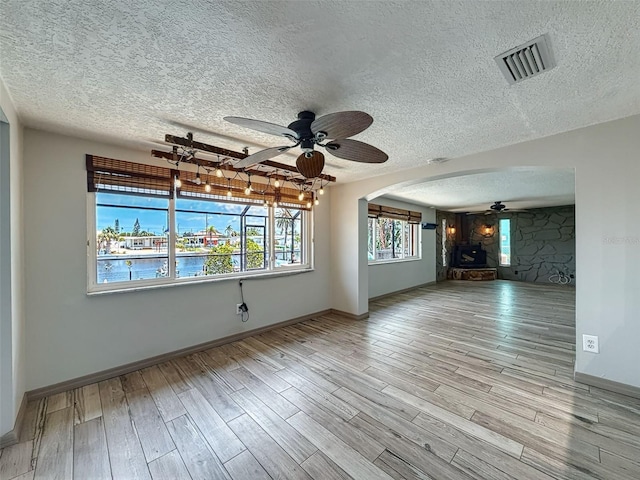 6601 Nautical Isle, Hudson, FL 34667 - unfurnished living room with a ceiling fan, arched walkways, a textured ceiling, wood finished floors, and baseboards