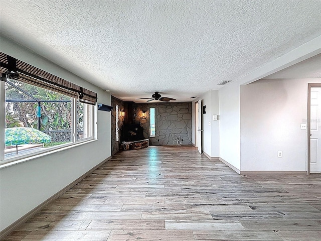6601 Nautical Isle, Hudson, FL 34667 - unfurnished living room featuring a textured ceiling, wood finished floors, ceiling fan, and baseboards