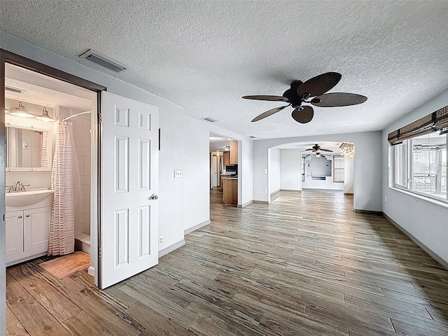 6601 Nautical Isle, Hudson, FL 34667 - unfurnished living room with ceiling fan, wood finished floors, a textured ceiling, a sink, and baseboards
