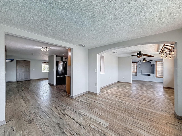6601 Nautical Isle, Hudson, FL 34667 - unfurnished living room with a ceiling fan, light wood-type flooring, a textured ceiling, arched walkways, and baseboards