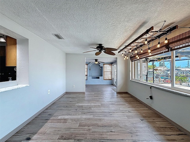 6601 Nautical Isle, Hudson, FL 34667 - unfurnished living room featuring a ceiling fan, wood finished floors, a textured ceiling, and baseboards