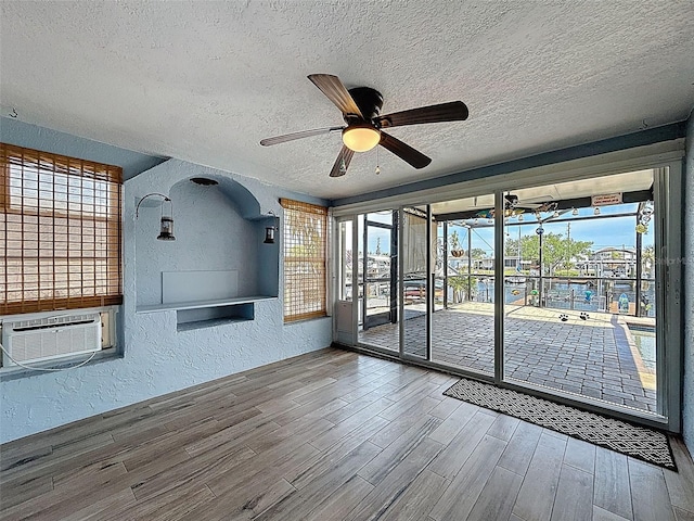 6601 Nautical Isle, Hudson, FL 34667 - empty room featuring a textured wall, a ceiling fan, a textured ceiling, wood finished floors, and plenty of natural light