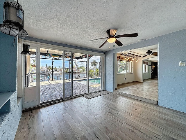 6601 Nautical Isle, Hudson, FL 34667 - empty room with a textured wall, a ceiling fan, a textured ceiling, wood finished floors, and baseboards