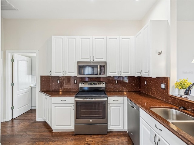 13922 Talmage Loop, Hudson, FL 34667 - kitchen featuring stainless steel appliances, a sink, white cabinetry, tasteful backsplash, and dark wood-style flooring