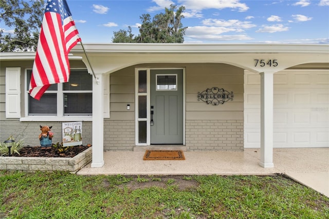 7545 Banner St, New Port Richey, FL 34653 - doorway to property featuring brick siding, a garage, and covered porch