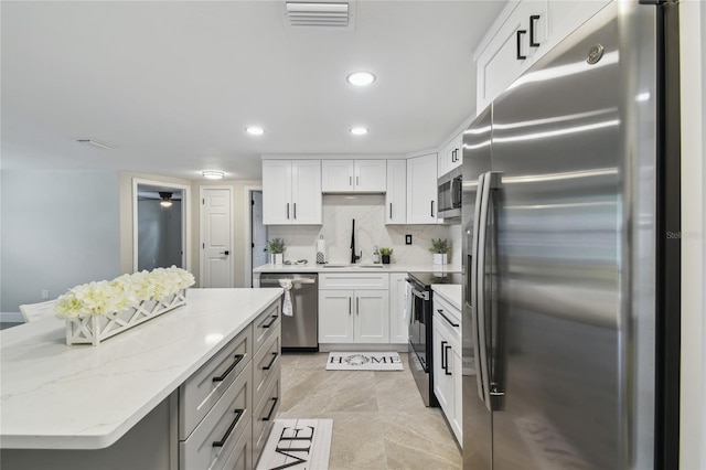 7545 Banner St, New Port Richey, FL 34653 - kitchen with stainless steel appliances, a sink, white cabinetry, tasteful backsplash, and a center island