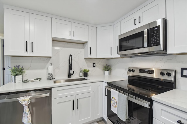 7545 Banner St, New Port Richey, FL 34653 - kitchen with stainless steel appliances, a sink, white cabinetry, and tasteful backsplash