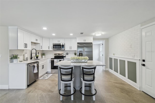 7545 Banner St, New Port Richey, FL 34653 - kitchen featuring appliances with stainless steel finishes, light countertops, a sink, white cabinets, and a center island