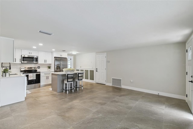 7545 Banner St, New Port Richey, FL 34653 - kitchen with appliances with stainless steel finishes, a center island, white cabinetry, a kitchen breakfast bar, and recessed lighting