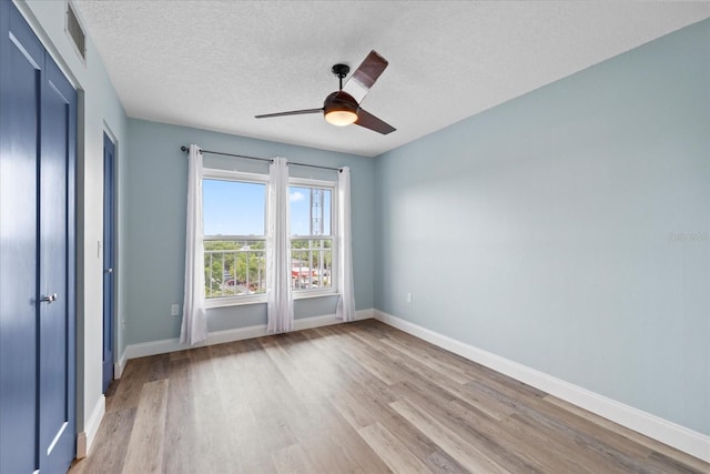 4939 Floramar Ter Unit 611, New Port Richey, FL 34652 - unfurnished bedroom featuring light wood-style flooring, baseboards, a textured ceiling, and a ceiling fan