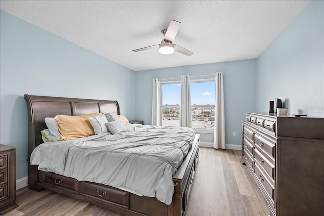 4939 Floramar Ter Unit 611, New Port Richey, FL 34652 - bedroom featuring light wood-type flooring, baseboards, a textured ceiling, and a ceiling fan