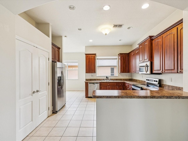 4266 High Ridge Ave, Spring Hill, FL 34609 - kitchen with stainless steel appliances, dark countertops, a sink, a peninsula, and light tile patterned flooring