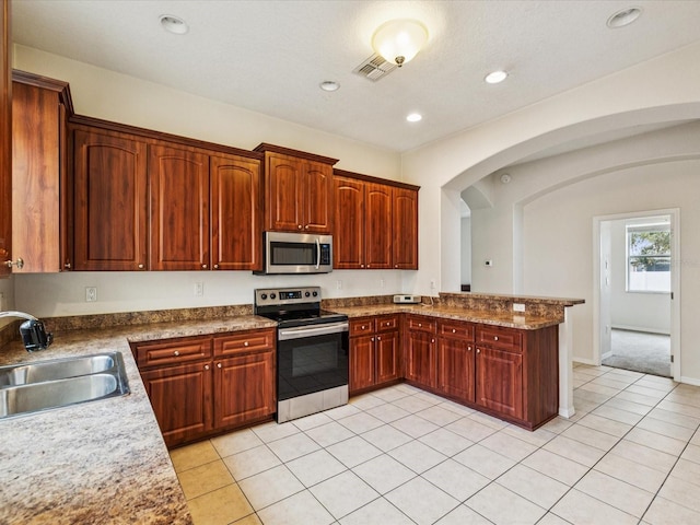 4266 High Ridge Ave, Spring Hill, FL 34609 - kitchen with stainless steel appliances, a sink, arched walkways, light tile patterned flooring, and a peninsula
