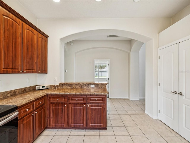 4266 High Ridge Ave, Spring Hill, FL 34609 - kitchen with arched walkways, stainless steel range with electric stovetop, dark stone counters, a peninsula, and light tile patterned floors