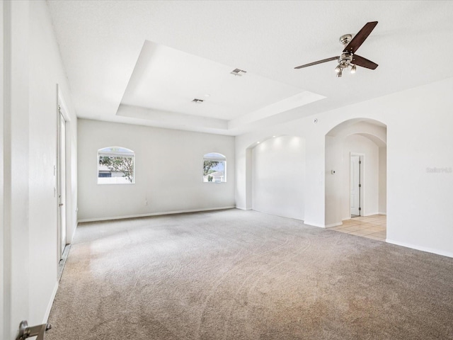 4266 High Ridge Ave, Spring Hill, FL 34609 - spare room featuring light colored carpet, a tray ceiling, a ceiling fan, and arched walkways