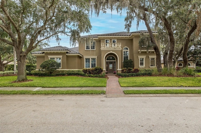 10531 Pontofino Cir, Trinity, FL 34655 - mediterranean / spanish home featuring a balcony, a tiled roof, stucco siding, and a front lawn