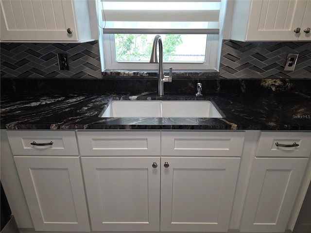 7313 Hatteras Dr, Hudson, FL 34667 - kitchen with a sink, white cabinets, decorative backsplash, and dark stone countertops