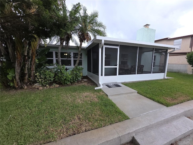 7313 Hatteras Dr, Hudson, FL 34667 - rear view of house with a sunroom, a chimney, and a lawn