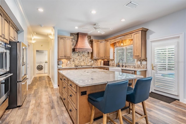 2880 Chelsea Pl N, Clearwater, FL 33759 - kitchen featuring premium range hood, washing machine and clothes dryer, a kitchen bar, freestanding refrigerator, and a kitchen island