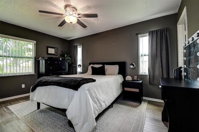 10670 43rd St N Unit 204, Clearwater, FL 33762 - bedroom with multiple windows, wood finished floors, a textured ceiling, baseboards, and ceiling fan