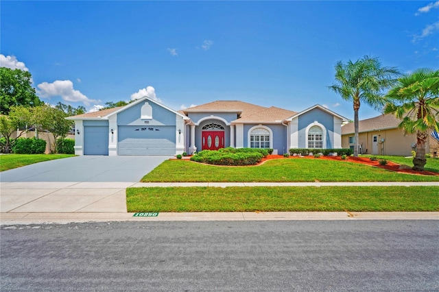 10250 Locker Dr, Spring Hill, FL 34608 - mediterranean / spanish house with an attached garage, a front lawn, driveway, and stucco siding