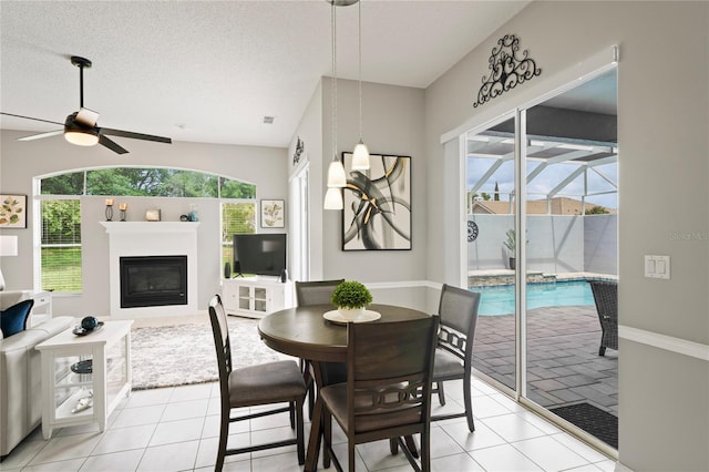 10250 Locker Dr, Spring Hill, FL 34608 - dining room with ceiling fan, light tile patterned floors, healthy amount of natural light, and a glass covered fireplace