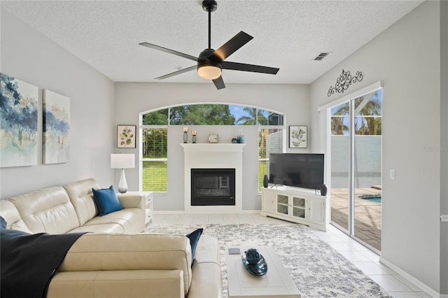 10250 Locker Dr, Spring Hill, FL 34608 - living area featuring a ceiling fan, a textured ceiling, a glass covered fireplace, baseboards, and tile patterned floors