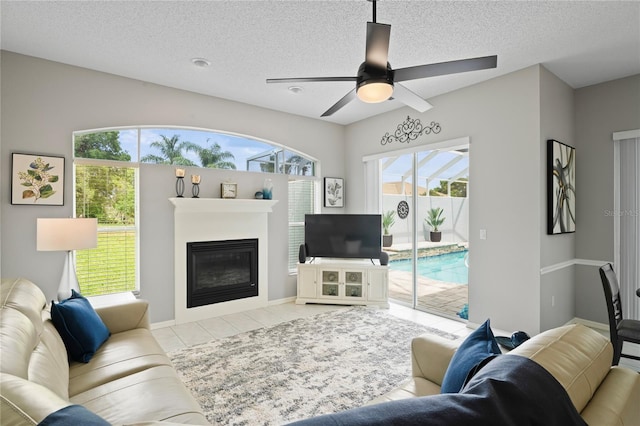 10250 Locker Dr, Spring Hill, FL 34608 - living room with healthy amount of natural light, a textured ceiling, a glass covered fireplace, ceiling fan, and baseboards