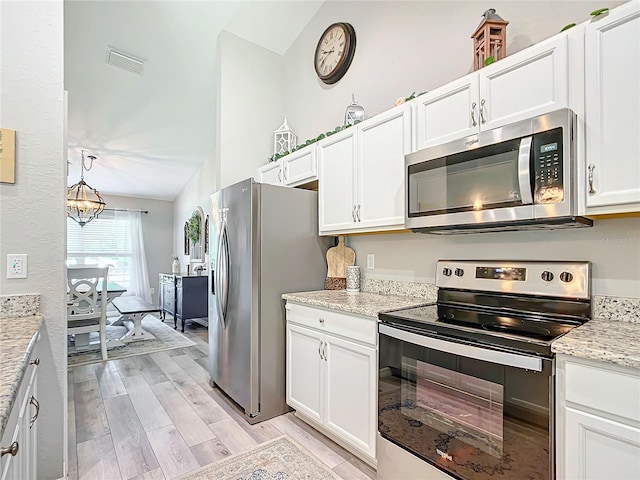 12396 SW 64th Street Rd, Ocala, FL 34481 - kitchen with stainless steel appliances, vaulted ceiling, light wood-style floors, white cabinets, and a chandelier
