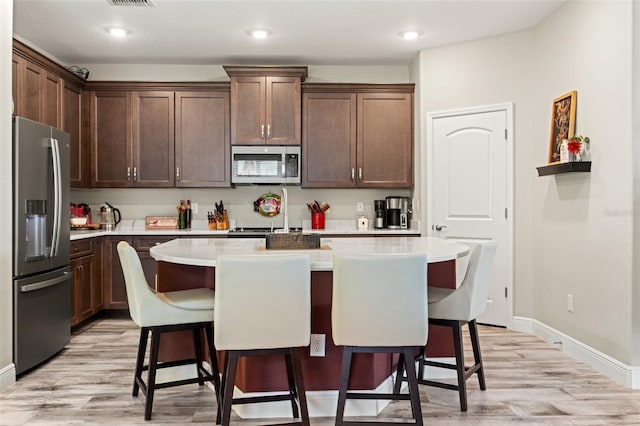 11579 Weaver Hollow Rd, New Port Richey, FL 34654 - kitchen with stainless steel appliances, light wood-style flooring, light countertops, a kitchen breakfast bar, and baseboards